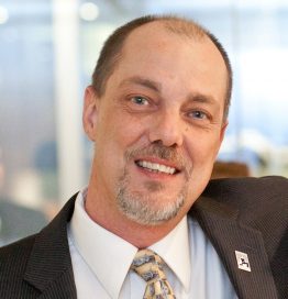 Bio photo of Scott Giacoppo, smiling in a white, dark jacket and tie